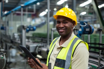 Smiling factory worker using a digital tablet in the factory