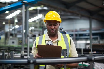 Factory worker looking at clipboard in factory