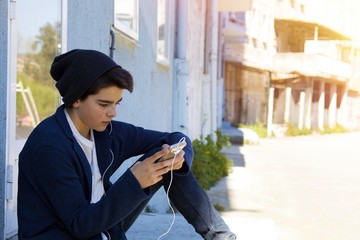 child with a mobile phone in the street about the blue wall