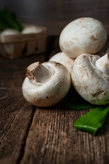 Fresh white mushrooms champignon in brown bowl on wooden background. Top view.
