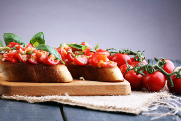 Fototapeta na wymiar Tasty savory tomato Italian appetizers, or bruschetta, on slices of toasted baguette garnished with basil