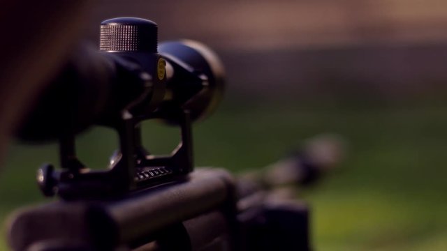 Hunter adjusting snipe rifle scope