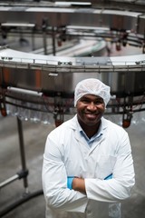 Smiling factory engineer with arms crossed 