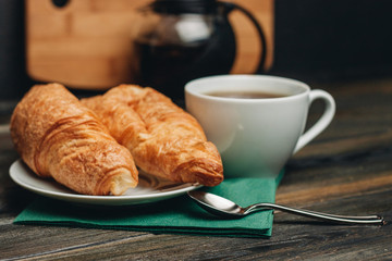 two croissants in a plate and a drink in a cup