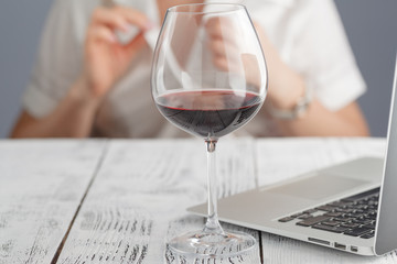Female drink wine at office. Work time end