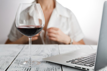 Woman end of works with glass of red wine tablet and laptop