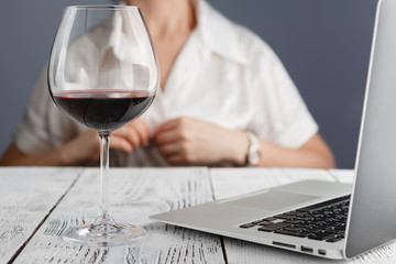 Woman end of works with glass of red wine tablet and laptop
