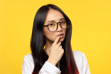 a puzzled woman with glasses touches her face with a finger
