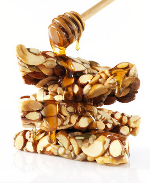 Nut bard with honey drizzling from spoon