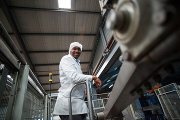 Fototapeta premium Smiling factory engineer standing in bottle factory