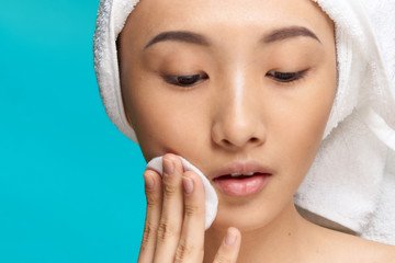 woman wiping her face with a cotton pad