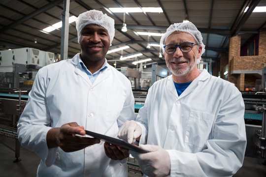 Two factory engineers with digital tablet smiling 