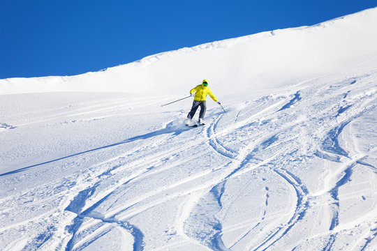 Male skier running downhill on slope at sunny day