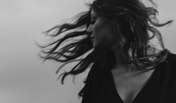 Woman tossing hair at sullen sky background - motion blur