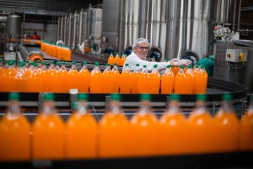 Factory engineer monitoring filled juice bottle 