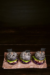 Delicious and juicy black burger with a large cutlet of meat on a black background