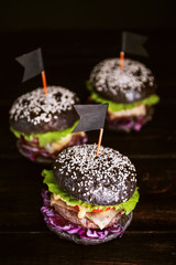 Delicious and juicy black burger with a large cutlet of meat on a black background