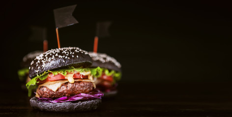 Delicious and juicy black burger with a large cutlet of meat on a black background