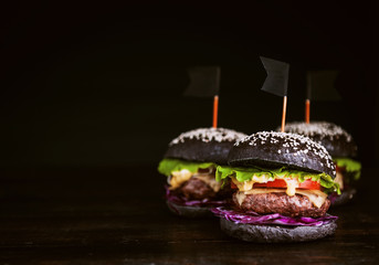 Delicious and juicy black burger with a large cutlet of meat on a black background