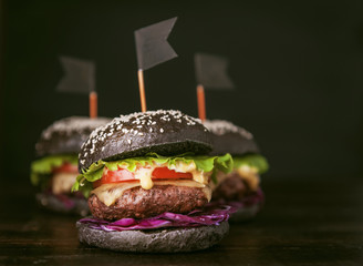 Delicious and juicy black burger with a large cutlet of meat on a black background