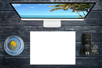 Desktop display with camera and empty paper on wooden table, traveling concept