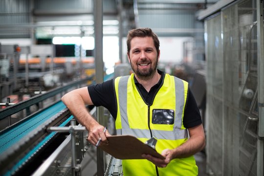 Portrait of factory worker standing with clipboard