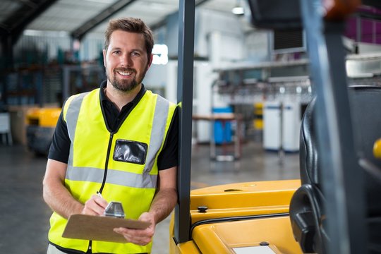 Factory worker writing on clipboard in factory