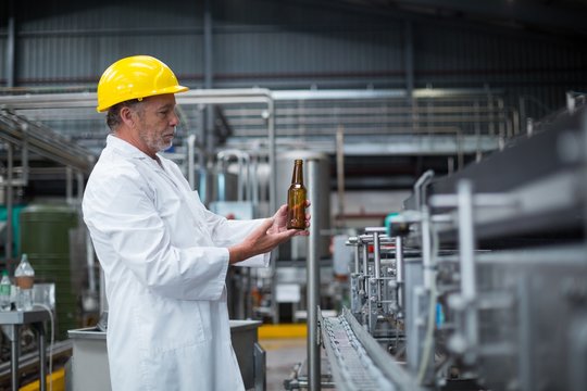 Factory worker examining a bottle in factory