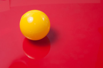 Plastic yellow ball on a red background