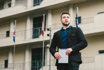 Outdoor portrait of a young man with a Tablet PC in the hands against the background of the building. Business concept