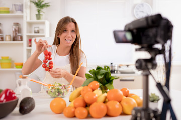 Beautiful young woman filming her blog broadcast about healthy food at the home.