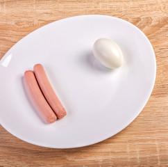 Two frankfurter sausages and egg on white plate on kitchen table.Close up shoot and top of view