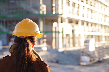 Baugewerbe, Frau mit Schutzhelm und Plänen auf einer Baustelle - obrazy, fototapety, plakaty