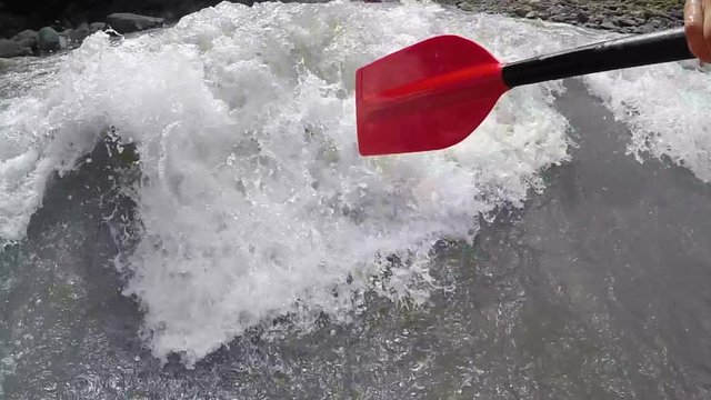 Athlete paddling in rafting boat, trying to withstand disastrous waves of river