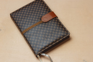 Top view of close up notebook dark cover on bright desk background