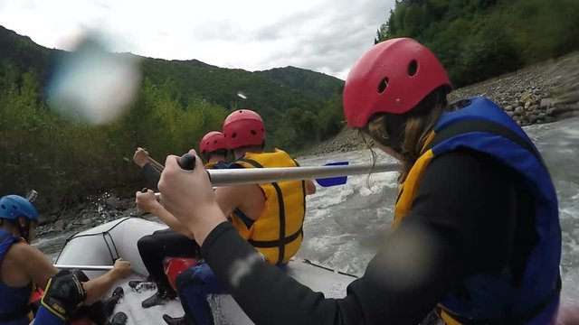 Rafting team working hard to maneuver along wild mountain river, togetherness