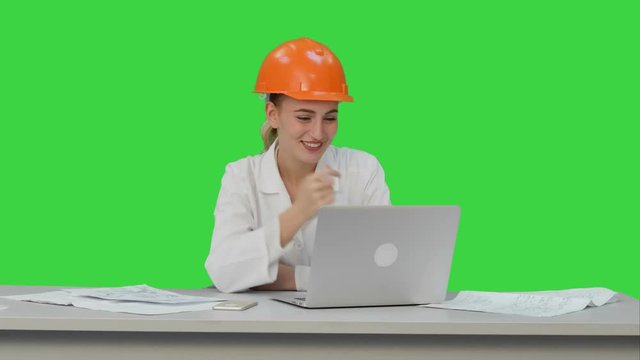 Female construction specialist in hardhat have online video chat with friend on a Green Screen, Chroma Key.