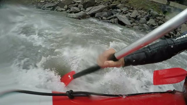 Rafter hardly overcoming steep rapids and underwater rocks of troubled river