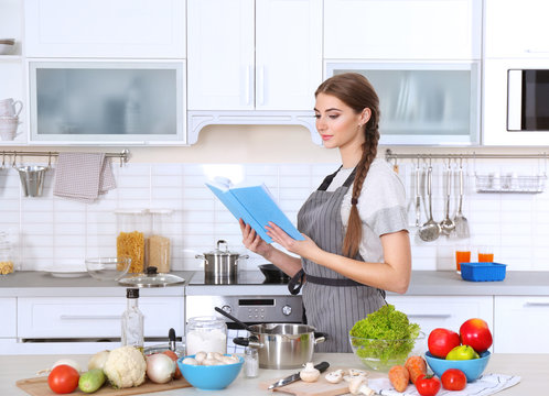 Young woman with cookbook at kitchen