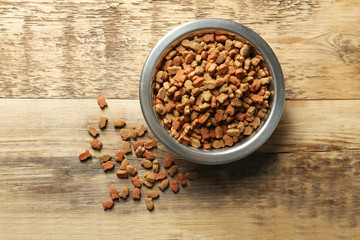 Cat food in bowl on wooden background
