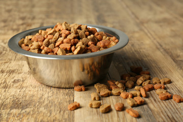 Cat food in bowl on wooden background