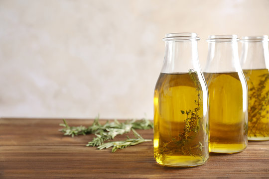 Bottles with herbs and oil on table