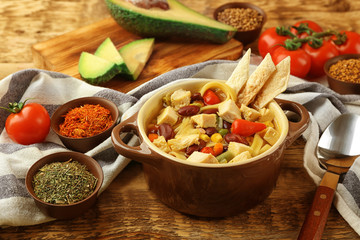 Chicken tortilla soup with vegetables on wooden table