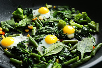 Delicious roasted quail eggs with spinach and french bean on pan, closeup