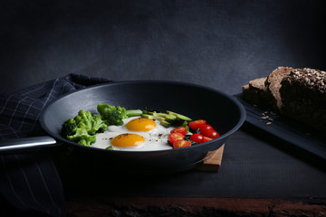 Tasty breakfast with eggs and vegetables in pan on table