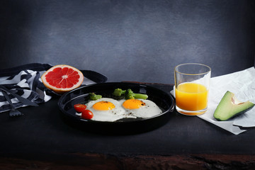 Tasty breakfast with eggs, vegetables and juice on table
