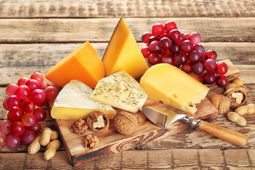 Board with variety of cheese on wooden background
