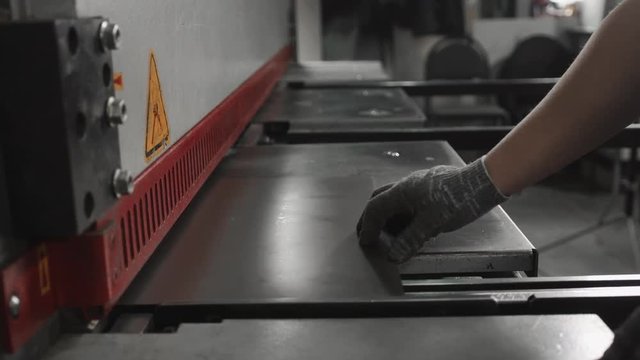 Worker bends a metal plate on the industrial machine for furniture line