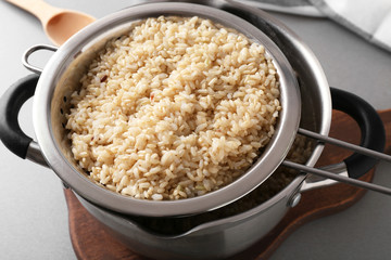 Colander with prepared brown rice in saucepan