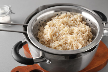Colander with prepared rice in saucepan